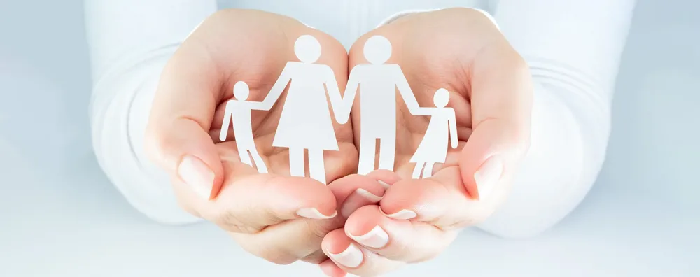 Paper cut-out family held in open hands